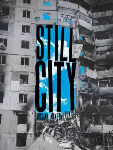Two photographed apartment buildings, one blasted into rubble, frame a bright-blue sky. "Still City" is printed between them in elongated, black letters.