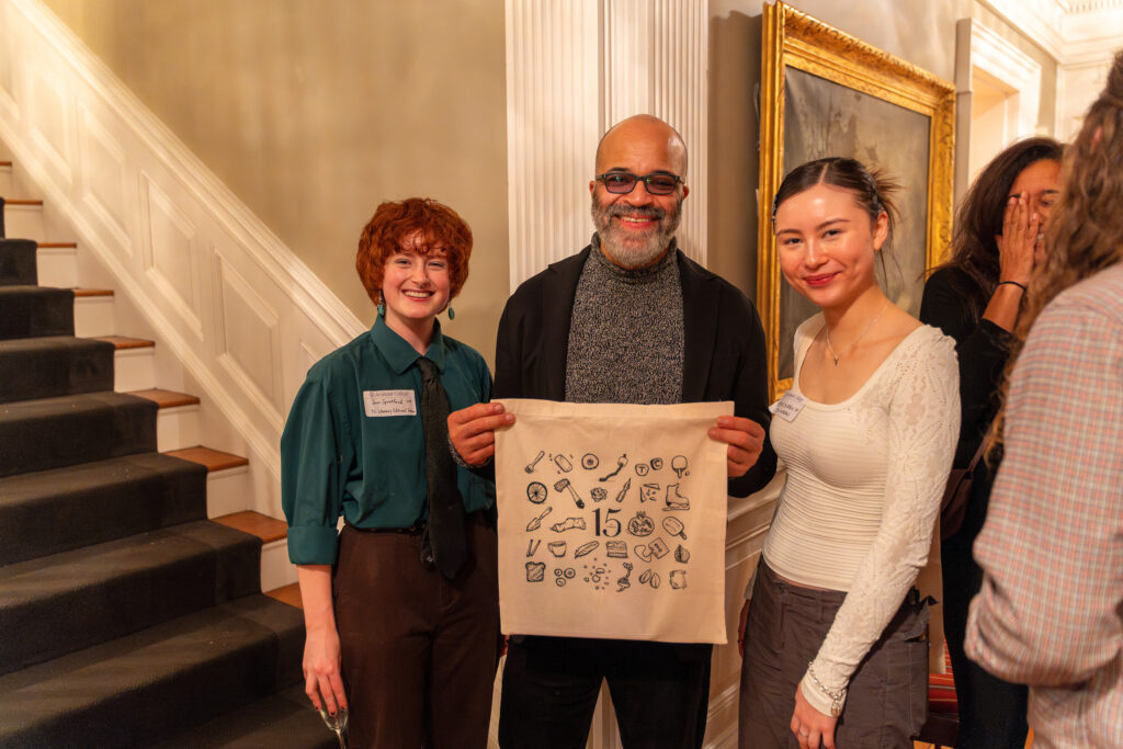 Wright smiling holding a TC tote bag, flanked by two TC interns.