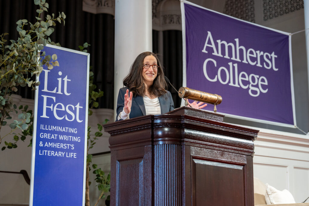 Acker addressing the crowd from a podium with large purple banners behind her reading "LitFest" and "Amherst College".