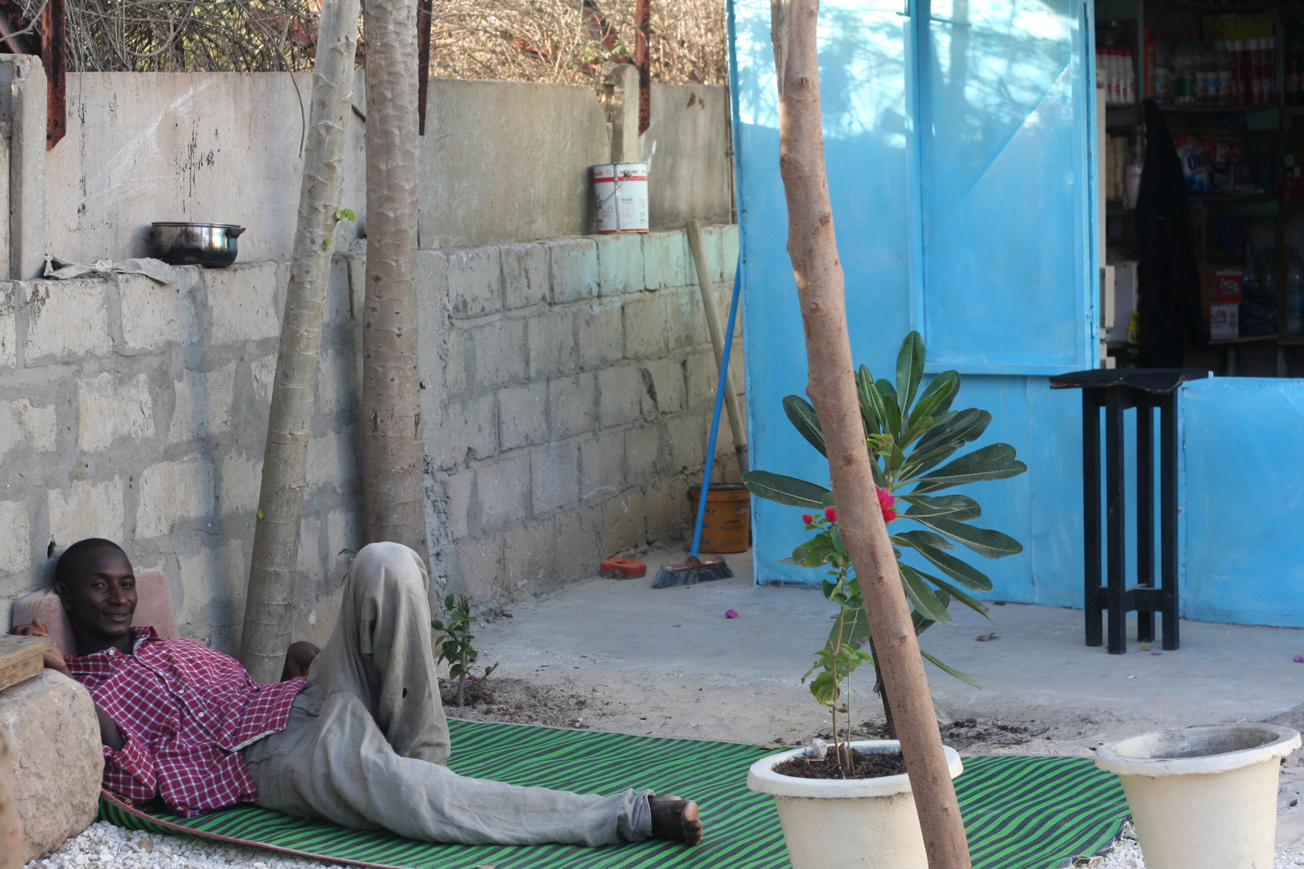 Naow reclines on a green mat by a wall. 